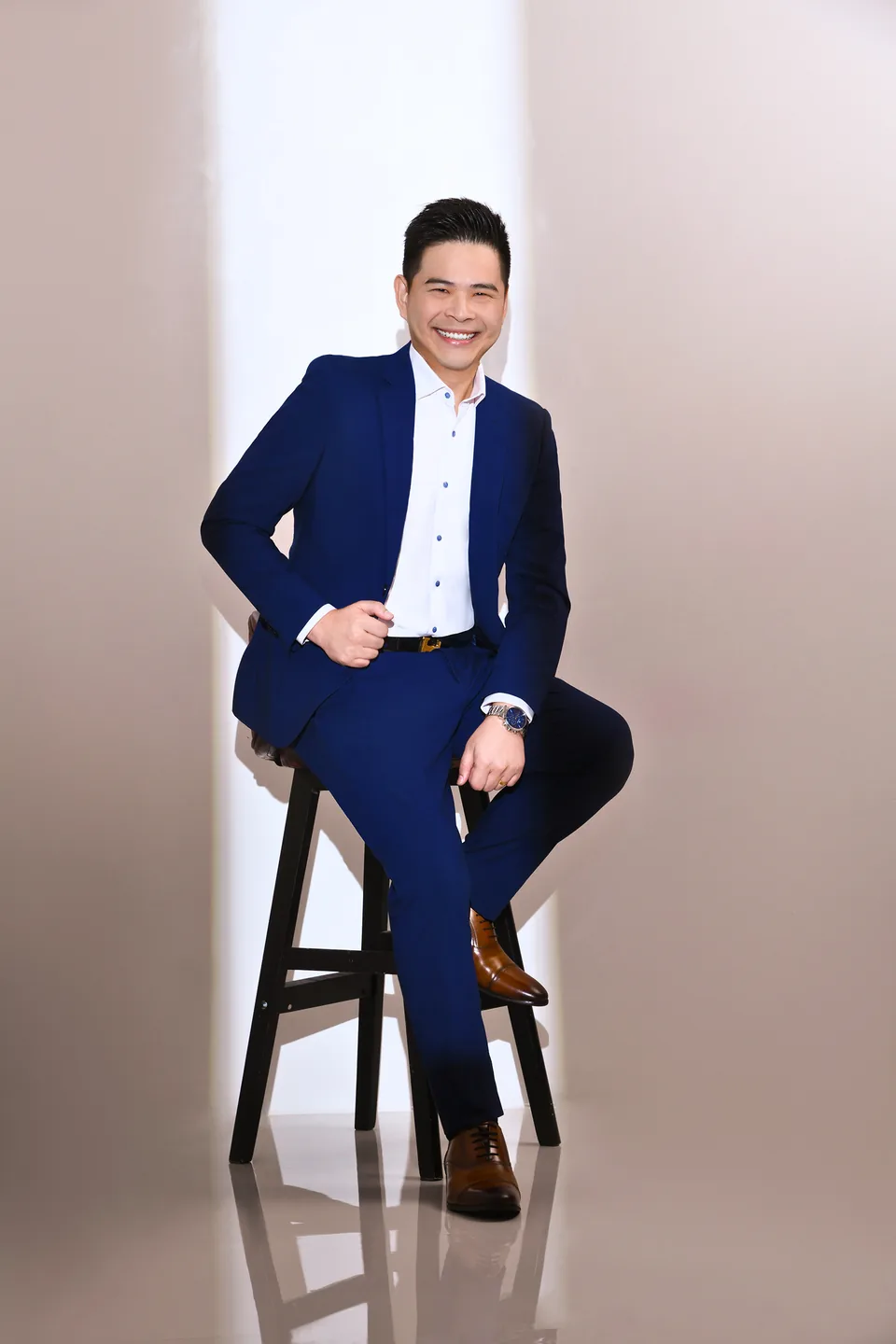 John Tan seated, in a navy suit