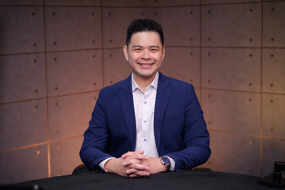 John Tan seated at a desk, ready for a first conversation